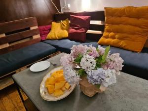 a table with a bowl of fruit and flowers on it at BroBro hostel in Tbilisi City