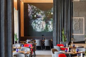 un ristorante con tavoli e sedie e un grande schermo di Qosmo Brasov Hotel a Braşov