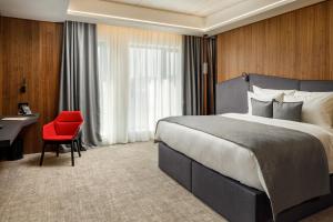 um quarto de hotel com uma cama grande e uma cadeira vermelha em Qosmo Brasov Hotel em Braşov mais 37 fotografias