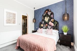 een slaapkamer met een groot bed met een bloemrijk hoofdeinde bij L-Spa Boutique Apartments in Leamington Spa
