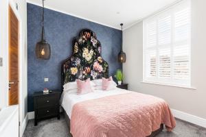 a bedroom with a large bed with a floral headboard at L-Spa Boutique Apartments in Leamington Spa