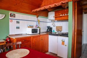 a small kitchen with a white microwave and a stove at Casas Tipicas Candelaria Tabua in Ponta do Sol