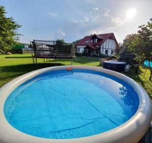 a large blue swimming pool in a yard with a house at Ośrodek Wypoczynkowo Sportowy Pod Żurawiem in Lniano