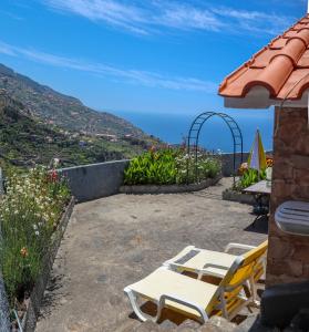 eine Terrasse mit einem Tisch, Stühlen und Meerblick in der Unterkunft Casas Tipicas Candelaria Tabua in Ponta do Sol