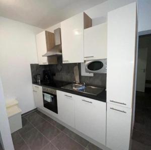 a kitchen with white cabinets and a sink at International 6 in Bad Harzburg +5 photos