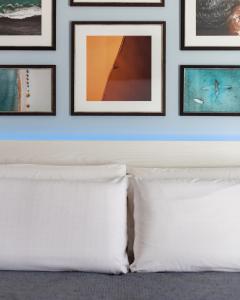 een slaapkamer met een wit kussen en ingelijste foto's bij J Rooms in Olbia