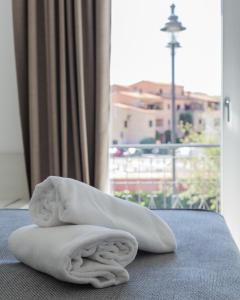 een stapel handdoeken op een bed met een raam bij J Rooms in Olbia