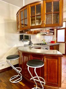 a kitchen with wooden cabinets and two bar stools at Peru Star Apart-Hotel in Lima