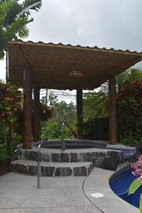 a large pool with a stone wall and a bench at Hotel Roca Negra Del Arenal in Fortuna