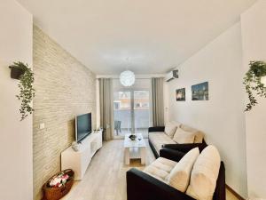 uma sala de estar com um sofá e uma televisão em Olive Square Apartment Budva em Budva