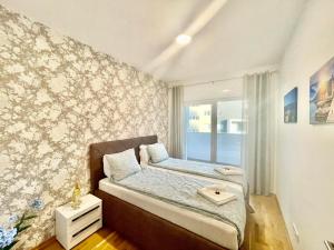 - une chambre avec un lit et un mur orné de papier peint floral dans l'établissement Olive Square Apartment Budva, à Budva