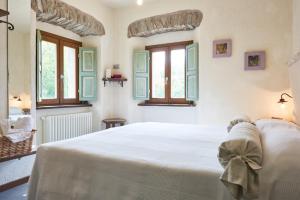 a bedroom with a large white bed with windows at Mulino Marghen - Agriturismo e Retreat Center in Zeri