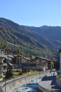 un río que fluye a través de una ciudad con montañas en el fondo en Haus Orta, en Zermatt