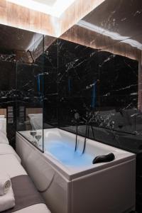 y baño con bañera y azulejos negros. en NOHO Boutique , premium living Lazeon 7, en Atenas 122 fotos más