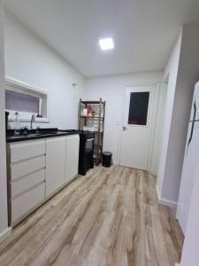 a kitchen with white cabinets and a wooden floor at Chalé do Bosque in Gramado