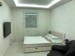a white room with a bed and a tv at Bezsó apartman in Hajdúszoboszló