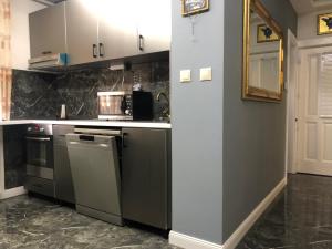 a kitchen with stainless steel appliances and gray cabinets at Bezsó apartman in Hajdúszoboszló