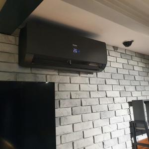 TV de pantalla plana colgada en una pared de ladrillo en Apartamenty Kąpielowa Czarny, en Ełk