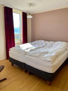 a large bed in a bedroom with a window at Syðstibær Guesthouse in Hrísey