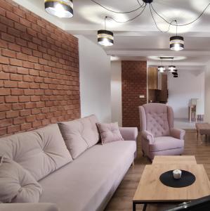 uma sala de estar com um sofá e uma parede de tijolos em Apartamenty Olimpijskie Szczyrk em Szczyrk