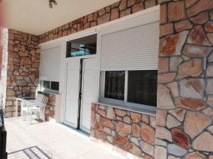 a stone wall with windows with blinds on it at Aquastelle est 2021 in Neos Marmaras