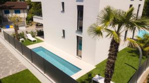 an external view of a house with a swimming pool and a palm tree at LUXURY apartment ROYAL IRIS in Njivice