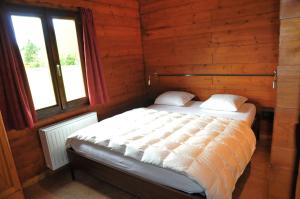 a bed in a wooden room with a window at Gite L'unité in Hour