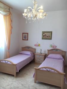 1 dormitorio con 2 camas y lámpara de araña en Appartamento Rocco, en Castro di Lecce