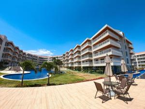 a large apartment building with a pool and tables and chairs at Solarium Residence no Porto das Dunas in Fortaleza