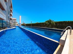 a swimming pool with blue water in a building at Solarium Residence no Porto das Dunas in Fortaleza