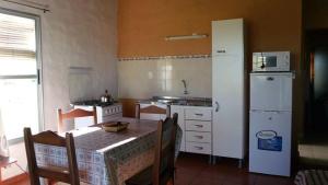 cocina con mesa y nevera blanca en Cabañas en Termas de Guaviyú, Paysandú, Uruguay en Quebracho