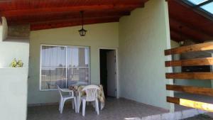 d'une terrasse avec une table, des chaises et une fenêtre. dans l'établissement Cabañas en Termas de Guaviyú, Paysandú, Uruguay, à Quebracho