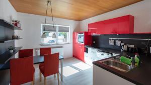 a kitchen with red cabinets and a black counter top at Hinter Burg, Haus mit Garten in Mayen