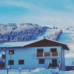 une maison dans la neige avec une montagne en arrière-plan dans l'établissement WiWa Appartement, à Flachau