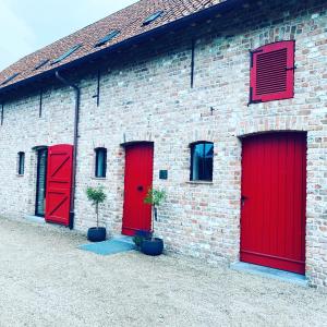 ein Backsteingebäude mit roten Türen und zwei Topfpflanzen in der Unterkunft Guesthouse Graaf Jan in Kaprijke