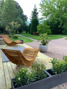 2 chaises assises sur une terrasse en bois dans un jardin dans l'établissement Par la Dives, à Saint-Pierre-sur-Dives
