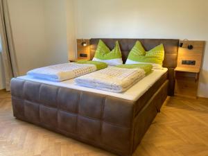 a large bed with a leather headboard and green pillows at Ansitz Hofer in Fulpmes