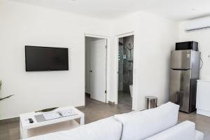 a white living room with a white couch and a tv at The Palm Leaf Apartments in Noord