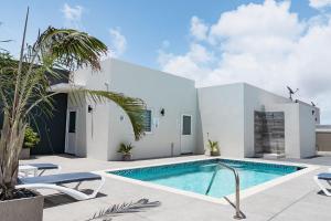 a swimming pool in front of a white house at The Palm Leaf Apartments in Noord