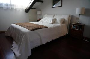 a bedroom with a white bed with a wooden floor at Stylish Penthouse Apartment in Venice Lido, 10 minutes from Saint Marks Square in Venice-Lido