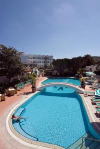 a large swimming pool in a resort with lounge chairs at Hotel Terme Villa Teresa in Ischia