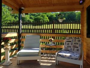 2 Stühle und ein Tisch auf einer Holzterrasse in der Unterkunft Bit Of Paradise in Râu de Mori