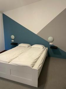 1 dormitorio con cama blanca y pared azul en Villa Darina, en Portorož