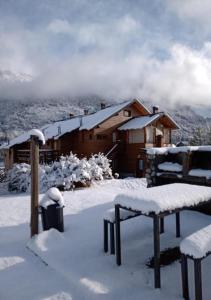 a cabin covered in snow with benches in front of it at Punto Bariloche in San Carlos de Bariloche