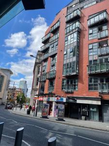 a tall red brick building on a city street at The Works - Private one bedroom apartment in Manchester