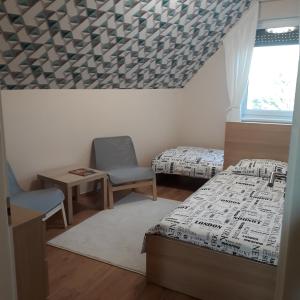 sypialnia z 2 łóżkami, krzesłem i oknem w obiekcie Belvárosi Apartman Lux w Hajduszoboszlo