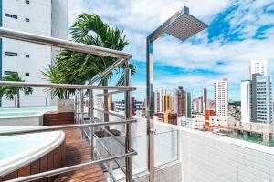 a balcony with a bathtub and a view of the city at GOLDFLAT Manaíra by PenareiaTurBr in João Pessoa