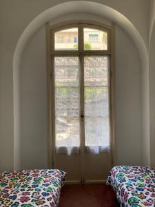 Habitación con ventana y cama delante. en Hôtel Belle Meunière, en Niza