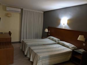 
a hotel room with two beds and two lamps at Torrejoven in Torrevieja
