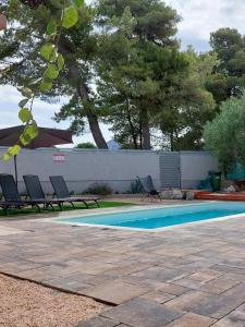 a swimming pool with two chairs and a fence at Kuća za odmor L&L in Bibinje